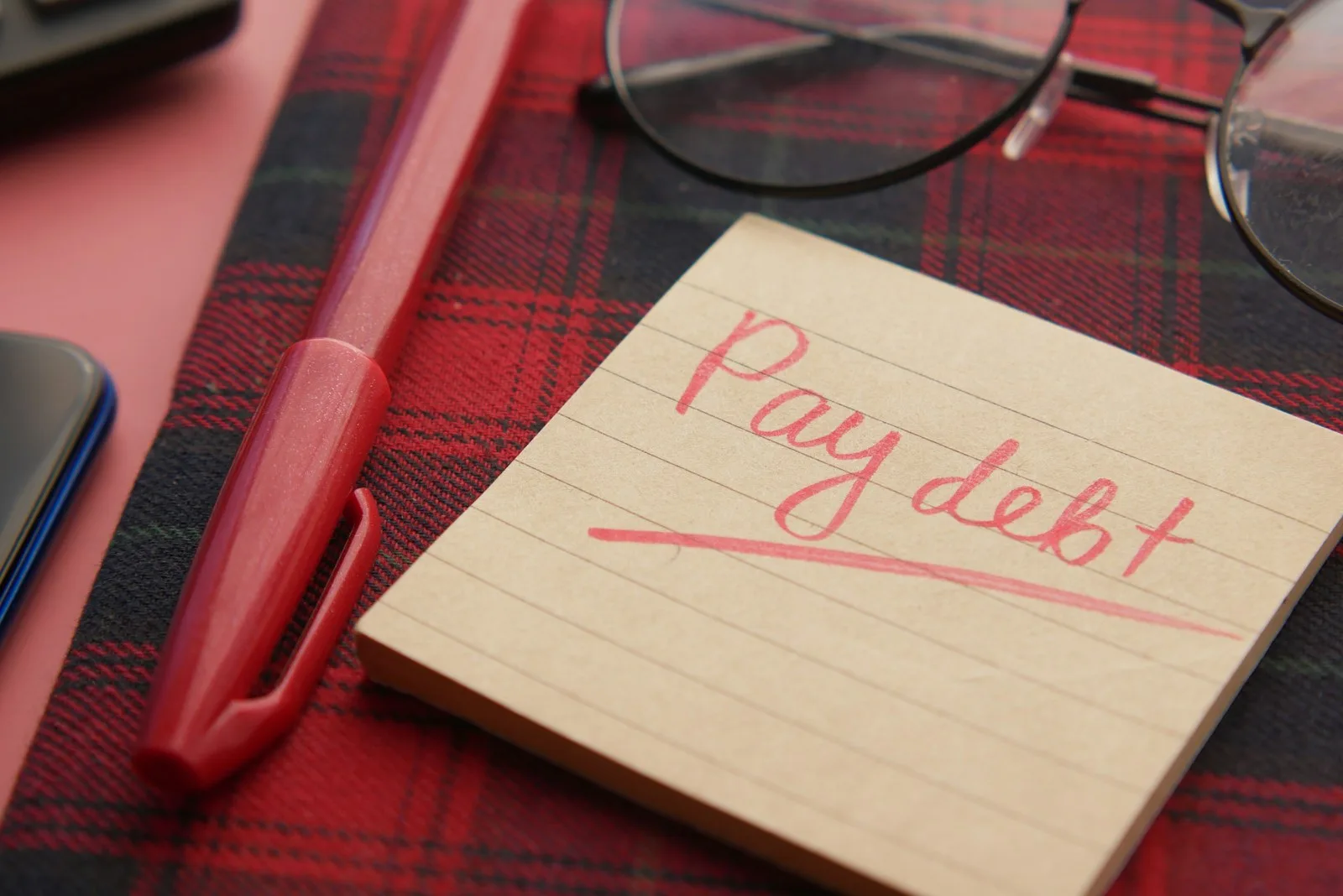 A sticky note with the word “Pay debt” written on it