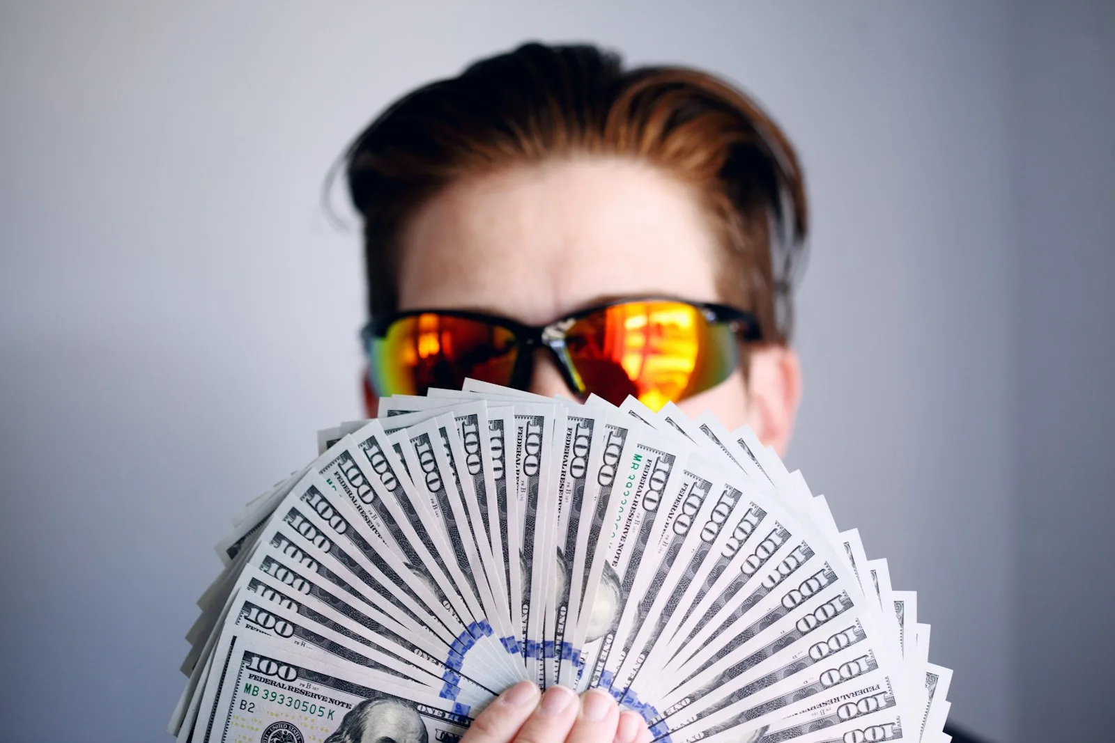 Photo of a shady person showing multiple $100 bills