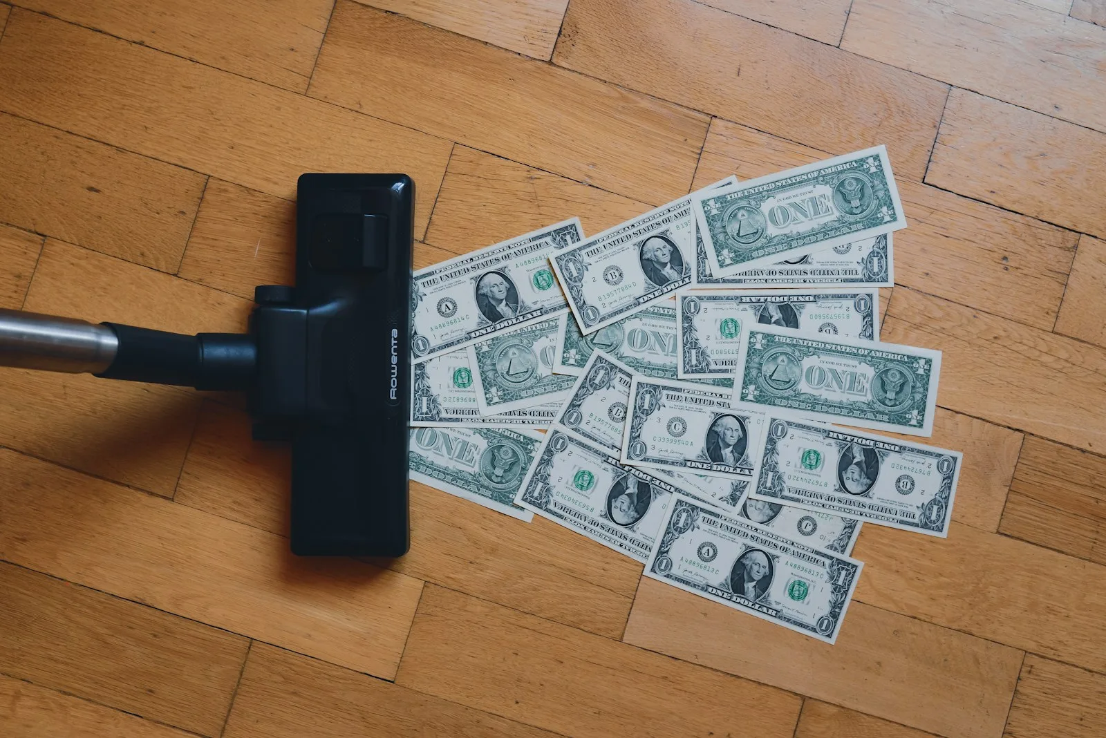 Image of a vacuum cleaner sucking away dollar bills. A sign of how debt eats aways all our savings.