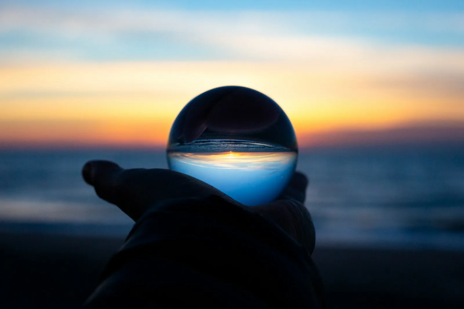 Photo of a glass ball held in front of a rising sun