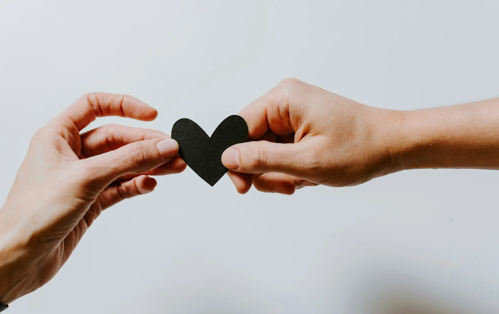 Two person holding a paper cut out in the shape of love